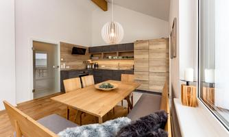 A modern kitchen with a wooden dining table and stylish chairs. The room design is bright and inviting, with natural materials and a cozy atmosphere.