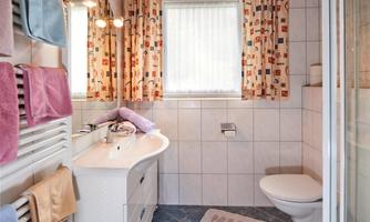 A bright bathroom with a modern sink installation. Colorful towels and curtains add a cheerful accent.