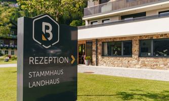 A modern reception sign shows the way to the reception of a country house. In the background, a stylish building with a garden can be seen.