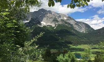 A majestic mountain with snow-capped peaks and lush green in the foreground. The sky is clear and blue, highlighting the beauty of the landscape.