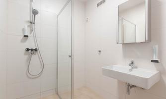 A modern bathroom with a shower cubicle and a sink. The walls are painted in light colors, and the furnishings are simple and functional.