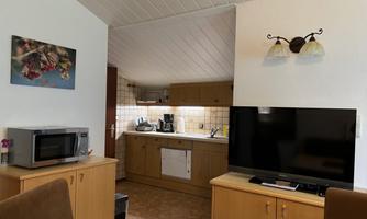 A cozy living kitchen with modern furnishings. The room features a television, a microwave, and a kitchenette.