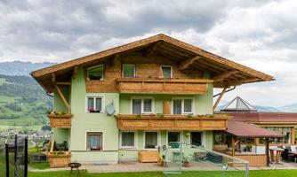A charming house with wood siding in nature. The surroundings are green and offer a panoramic view of the mountains.