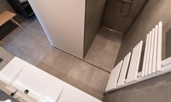 A modern bathroom with a shower and elegant tiles. The walls are in neutral colors, and a towel warmer is visible.