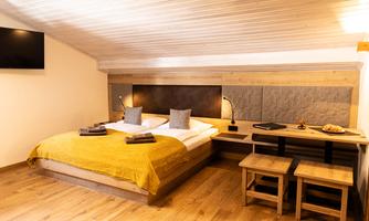 A modern bedroom with a double bed and warm colors. A desk and a television complement the cozy atmosphere.