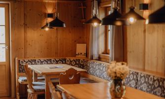 A cozy wooden room with a long table and benches. Soft lighting creates an inviting atmosphere.