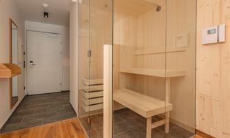 A modern sauna with wooden paneling and glass walls. The space is bright and invites relaxation.
