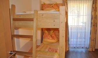 A cozy room with a wooden bunk bed. Soft pillows and bright curtains create an inviting atmosphere.