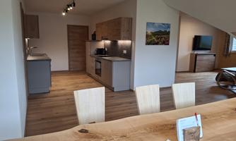 A modern kitchen with light wood surfaces and a dining area. The space is designed to be friendly and inviting.