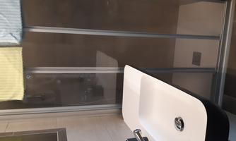 A modern bathroom with a shower and a sink. Two towels in soft colors are hanging.