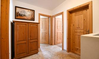 A spacious hallway with a wooden box and several doors. A picture in a frame hangs on the wall.