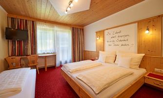 A beautiful hotel room with wooden walls and a large window. The decor is cozy and inviting.