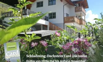 A cozy house in a picturesque landscape with flowers in the foreground. The Schladming-Dachstein Card is mentioned in the image.