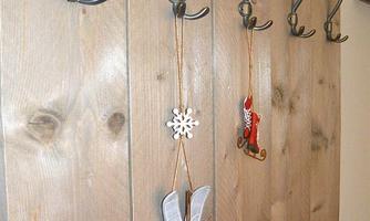 A wooden board with several hooks. Various decorations hang from the hooks, including a snowflake and a decorative skate.