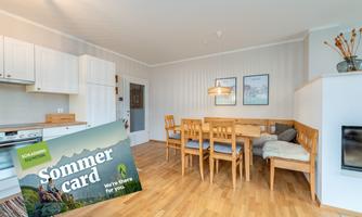 A bright, inviting dining room with a large table and chairs. In the foreground, there is a summer menu offering exciting activities.