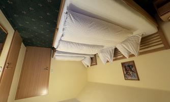 A simple room with three beds and yellow walls. There is a mirror and a wooden door in the background.