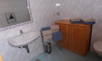 A simple bathroom with a sink and a wooden cabinet. Towels are neatly folded on a rack.