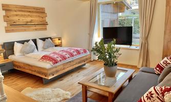 A cozy bedroom with a large bed and modern furniture. The room is bright and inviting, with a view of a garden.
