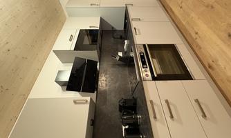A modern kitchen with light cabinets and a dark countertop. It is equipped with a stove, an oven, and various kitchen appliances.