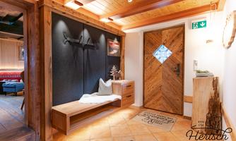 An inviting hallway with wood decor and a rustic entrance gate. Cushions are lying on the bench, and a cozy atmosphere prevails.