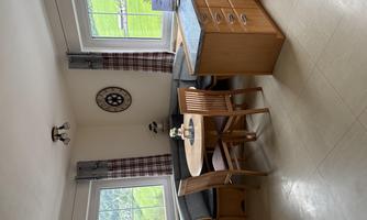 A bright room with a wooden table and chairs. The provider has a cozy dining area with windows and a clock on the wall.