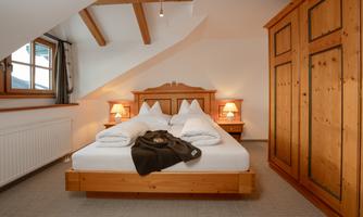 A cozy bedroom with a double bed and wooden furniture. Soft lighting creates an inviting atmosphere.