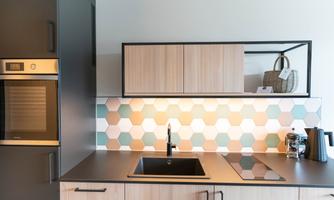 A modern kitchen with wooden cabinets and a stylish, bright backsplash. The kitchen appliances are elegantly and functionally integrated.