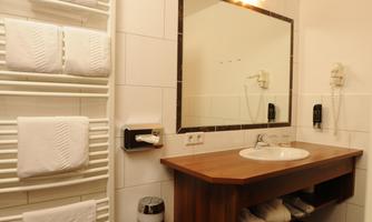 A modern bathroom with a sink and a mirror. Towels are neatly stacked, and there is a towel radiator.