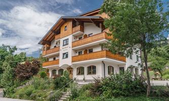A modern building with wooden decorations and balconies. Surrounded by trees and green landscapes.