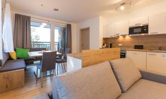 A modern apartment with an open living kitchen and a dining area. Large windows provide plenty of daylight and a cozy atmosphere.