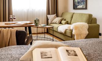 A cozy living room with a green sofa and a small table. In the room, there are two wine glasses and there is a warm, inviting atmosphere.