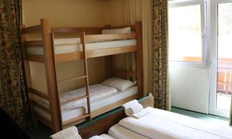 A simple bedroom with a bunk bed and a double bed. The windows provide plenty of daylight and a friendly atmosphere.
