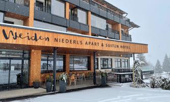 A modern hotel with wooden cladding, situated in the snow. The surroundings are wintry and inviting.