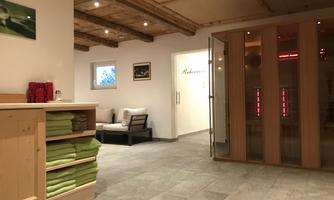 A relaxing wellness area with modern saunas and cozy seating. The walls are bright and the lighting creates a pleasant atmosphere.