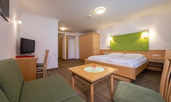 A cozy room with a double bed and modern furnishings. A small table and chairs as well as a television are also available.