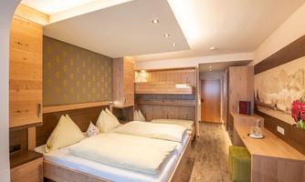 A modern hotel room with two beds and wooden-paneled walls. The cozy atmosphere is emphasized by warm lighting.