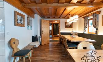 A cozy dining area with wooden details and large tables. The atmosphere is warm and inviting, perfect for social gatherings.