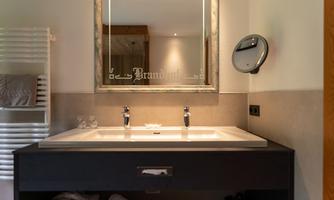 A modern bathroom with an elegant sink and a mirror. On the left side, towels and a towel rack are visible.
