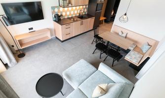 Bright, modern living kitchen with a cozy sofa and a dining table. The space is simply and stylishly furnished, ideal for relaxation and socializing.