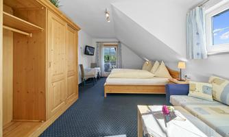 A cozy room with a double bed and a sofa. Bright colors and a window with a view create an inviting atmosphere.
