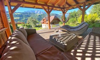 A cozy terrace with a wooden porch and a view of the mountains. Comfortable furniture invites you to relax.