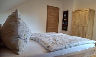 A cozy bedroom with a large bed and beautiful cushions. A wooden combination of wardrobe and door complements the decor.