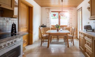 A cozy kitchen-dining room combination with wooden details. The table is set and there is a beautiful view through the windows.