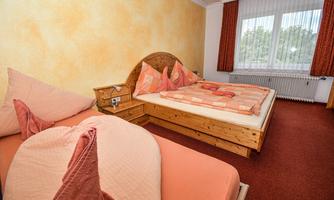 A cozy bedroom with two beds and a warm color scheme. The windows let in plenty of daylight and create an inviting atmosphere.