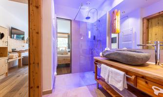 A modern bathroom with a glass shower and warm wood decor. The soft lighting creates a relaxing atmosphere.