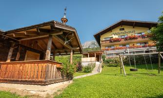 A typical inn with a wooden facade and balcony. Surrounded by green grass and playground equipment.