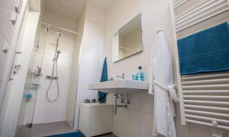 A modern bathroom with a shower and a sink. Towels and toiletries are in blue and white.