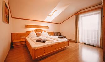 A cozy bedroom with a large bed and wooden furniture.  
Plenty of daylight streams through the window, creating an inviting atmosphere.