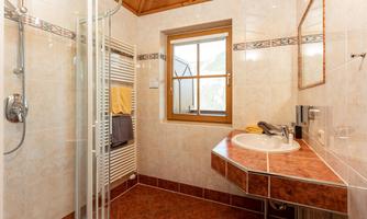 A modern bathroom with a shower cubicle and a sink. A window provides natural light and a pleasant atmosphere.