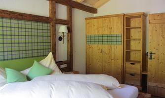 A cozy bedroom with wooden furniture and a comfortable bed. The walls are painted in light colors and decorated with checkered elements.